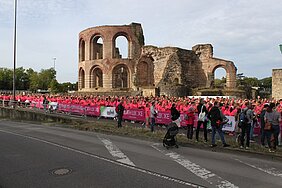 Große Menschenmenge in pinken Laufshirts vor einer antiken römischen Ruine bei einem Lauf-Event