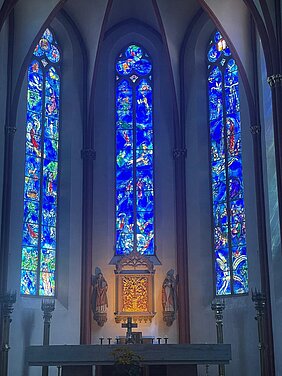 Foto aus dem Innenraum der Kirche St. Stephan in Mainz. Im Mittelpunkt ein Altar und darüber im Hinergrund mehrfarbige Glasfenster von Marc Chagall Foto aus dem Innenraum der Kirche St. Stephan in Mainz. Im Mittelpunkt ein Altar und darüber im Hinergrund mehrfarbige Glasfenster von Marc Chagall