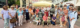 Gruppe von Frauen steht in einer Fußgängerzone neben einer Statue eines Polizisten in Uniform